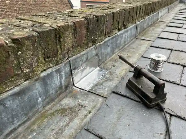 Chéneau en zinc réparé par une pièce soudée à l'étain