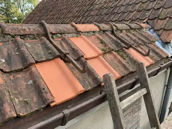 Quelques tuiles de rive remplacées sur une toiture en terre cuite
